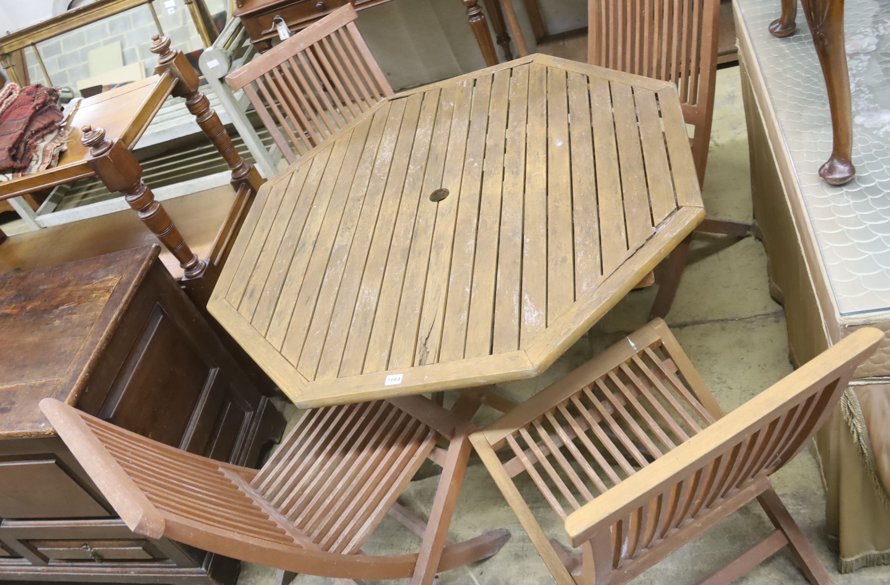 An octagonal teak garden table, width 111cm, height 69cm and four chairs